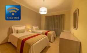 a hotel room with two beds and a free wifi sign at Flor Da Rocha in Portimão