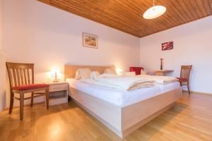 a bedroom with a large white bed and a chair at Haus Roswitha in Flachau