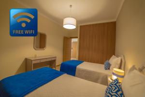 a hotel room with two beds and a free wifi sign at Flor Da Rocha in Portimão