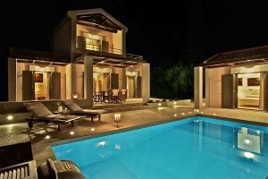 a swimming pool in front of a house at night at Elaia Villas in Minia