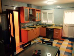 een keuken met oranje en blauwe kasten en een tafel bij Apartamentos Doñana in Sanlúcar de Barrameda