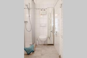 uma casa de banho branca com um chuveiro e um WC. em Enjoy Leipzig em Leipzig