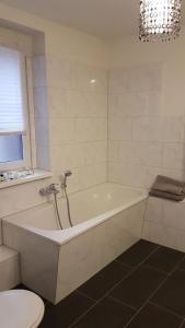 a white bathroom with a tub and a toilet at Pension Altes Forstamt in Eberswalde