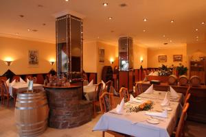 a restaurant with white tables and a wine barrel at Hotel Restaurant zum Schlossberg in Wadern