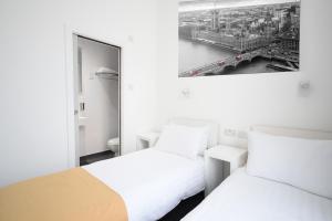 a hotel room with two beds and a mirror at Hotel Meridiana in London