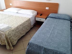 a hotel room with two beds and a wooden headboard at Hotel Madrid in Riccione