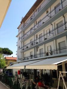 a building with tables and chairs in front of a building at Hotel Madrid in Riccione