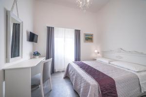 a white bedroom with a desk and a bed at Incentro in Gallipoli