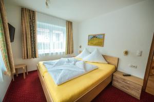 ein Hotelzimmer mit einem gelben Bett und einem Fenster in der Unterkunft Chalet Bernegg in Sautens