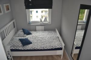 ジブヌベクにあるApartament Lesny Zakatekの小さなベッドルーム(青い枕と窓付きのベッド付)