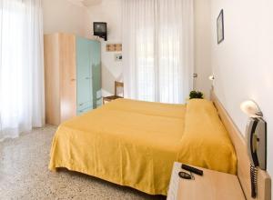 um quarto de hotel com uma cama amarela e uma secretária em Hotel Ferrara em Cattolica