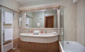 a bathroom with a sink and a tub and a mirror at Hotel Excelsior - Liburnia in Lovran