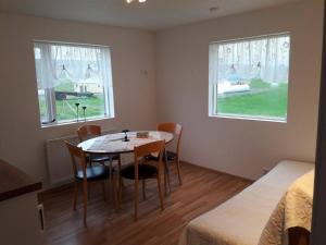 a room with a table and chairs and two windows at Sandhaugar Guesthouse in Kiðagil