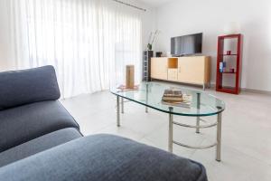 a living room with a glass table and a couch at Bright villa with salt water pool in El Campello
