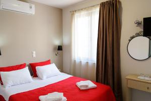 um quarto com uma cama vermelha com duas toalhas em LUX Hotel em Piraeus