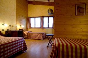 a room with two beds and a wall with windows at Hotel La Pigna in Bardonecchia