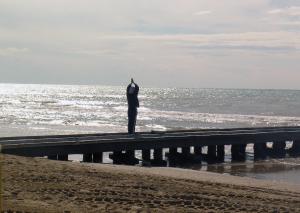 Un uomo che sta su un molo guardando l'oceano di Hotel Dante a Lido di Jesolo