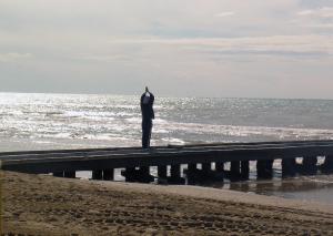 un hombre parado en un muelle mirando al océano en Hotel Dante, en Lido di Jesolo