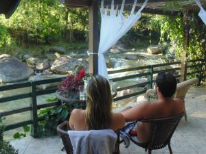 a man and woman sitting at a table looking at a river at Repousada Sana in Sana