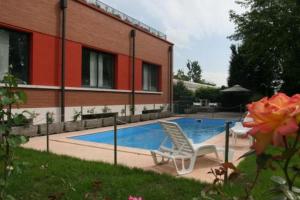 a swimming pool with two chairs next to a building at Airone Hotel in Reggio Emilia