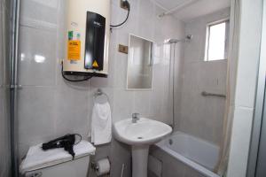 a white bathroom with a sink and a toilet at JMJ Departamentos Amoblados Ocarrol in Rancagua