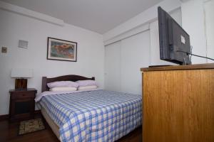 a bedroom with a bed and a flat screen tv at JMJ Departamentos Amoblados Ocarrol in Rancagua