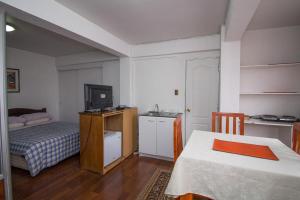 Habitación pequeña con cama, TV y mesa. en JMJ Departamentos Amoblados Ocarrol, en Rancagua
