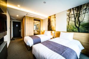 a hotel room with two beds and a tv at Gloucester Hotel Hamdeok in Jeju