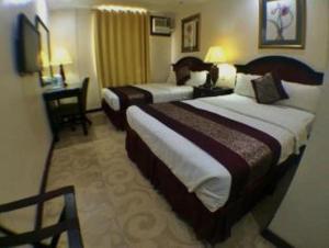 a hotel room with two beds and a desk at Cindy Kelly Hotel in Olongapo
