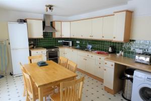 a kitchen with white cabinets and a wooden table at Castle Square Apartments Beaumaris in Beaumaris