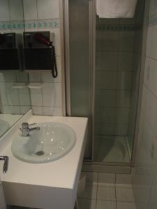 y baño con lavabo y ducha. en Hôtel Beauséjour, en Chaudes-Aigues