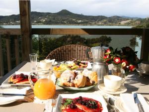 a table with plates of food and a view of the water at Bay of Islands Cottages in Russell