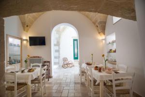 un comedor con mesas y sillas blancas y un arco en B&B Donnantonietta - Nobile dimora en Minervino di Lecce