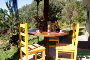 einen Holztisch und Stühle auf einer Terrasse in der Unterkunft Pousada Alto do Vale in Nova Friburgo
