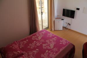 a room with a bed with a purple blanket and a window at Apartamento António in Praia