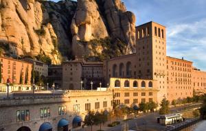 Un gran edificio con una montaña al fondo. en Apartamentos Montserrat Abat Marcet, en Montserrat