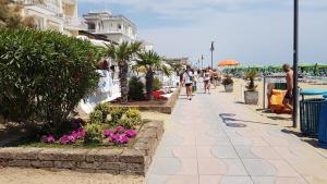 リド・ディ・イエゾロにあるVilla Picchetti Fronte Mareの浜辺の歩道を歩く人々