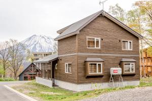 ein Holzhaus mit einem Berg im Hintergrund in der Unterkunft Kiseki in Niseko