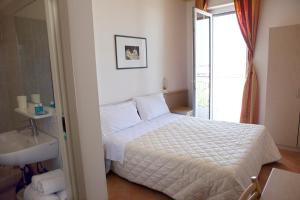 ein Schlafzimmer mit einem weißen Bett und einem Waschbecken in der Unterkunft Hotel Salsedine in Rimini