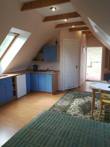 an attic kitchen with blue cabinets and a table at Namelis Nidoje in Nida