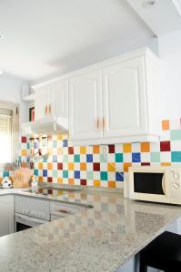 uma cozinha com armários brancos e azulejos coloridos na parede em Coral Dream em Las Palmas de Gran Canárias