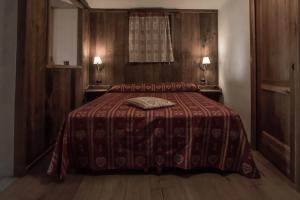 a bedroom with a bed with a blanket and two lamps at Lo Ni di Candolle in Gignod
