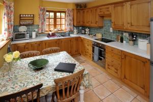 a kitchen with wooden cabinets and a table with chairs at Town End Farm Cottages in Taunton