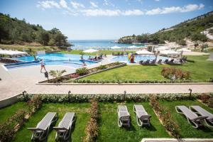 a resort with a pool and chairs and the ocean at Thassos Grand Resort in Alyki