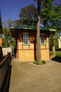 a small building with a tree in front of it at Alėjos Namelis in Palanga