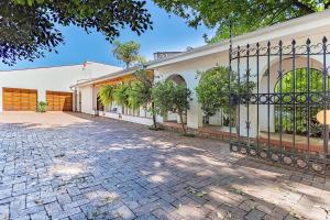 an entrance to a white building with a gate at Bay Tree Guest House in Pretoria