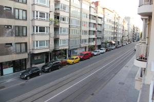 una strada con auto parcheggiate sul lato di un edificio di Royal Plage Oostende a Ostenda