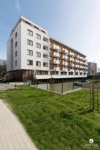 a large white building with a grassy field next to a building at Jantar Apartamenty City Center 2 in Kołobrzeg