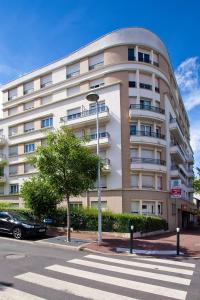 um grande edifício branco com uma árvore em frente em Séjours & Affaires Paris-Nanterre em Nanterre