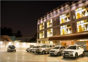un grupo de autos estacionados en un estacionamiento frente a un edificio en Hotel Ashoka, en Rameswaram